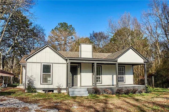 View of front of property with roof with shingles, covered porch, board and batten siding, and a chimney
