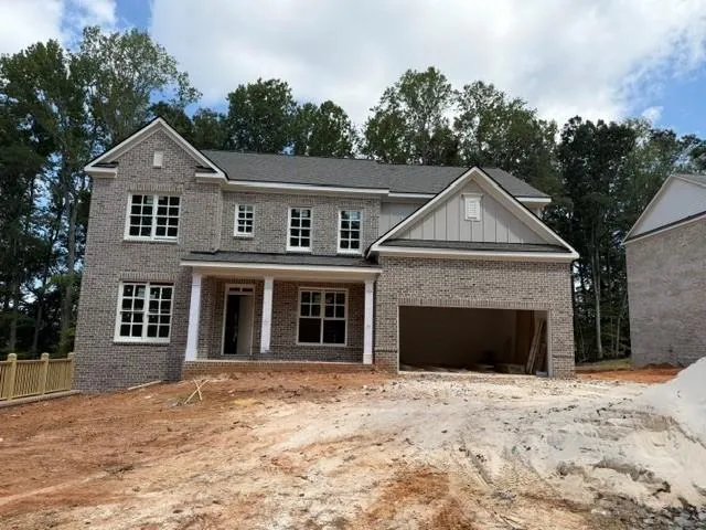 Two-story brick exterior, two-car garage, covered porch with columns, multiple pane windows, and a gabled roofline