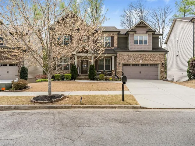 Brick and siding exterior with a covered front porch, an attached two-car garage, and a concrete driveway