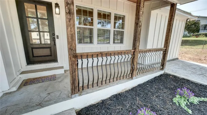 Front porch with wood posts, decorative metal railing, and board and batten siding