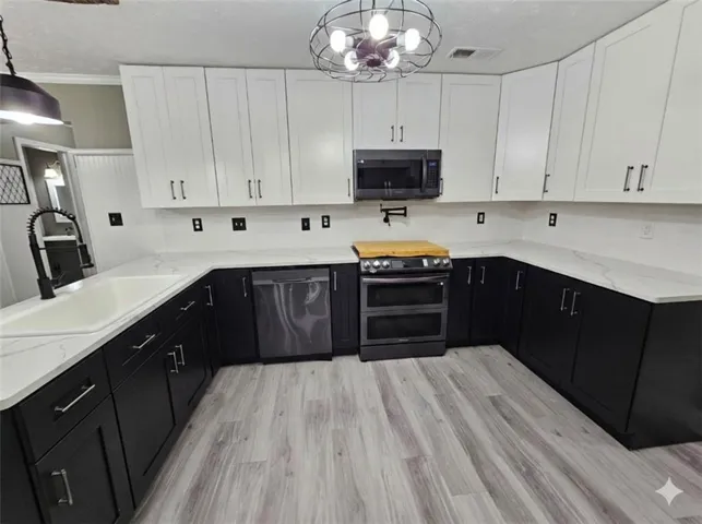 The kitchen features a U-shaped layout with two-tone cabinetry, white countertops