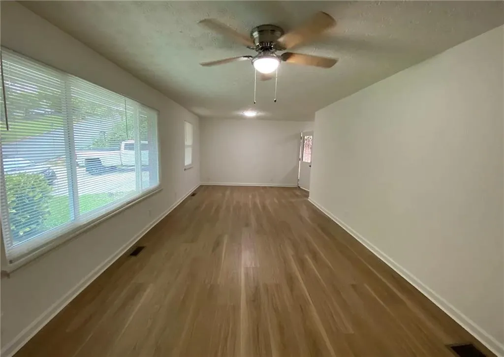 Unfurnished living room featuring dark wood-style flooring, ceiling fan, and a textured ceiling
