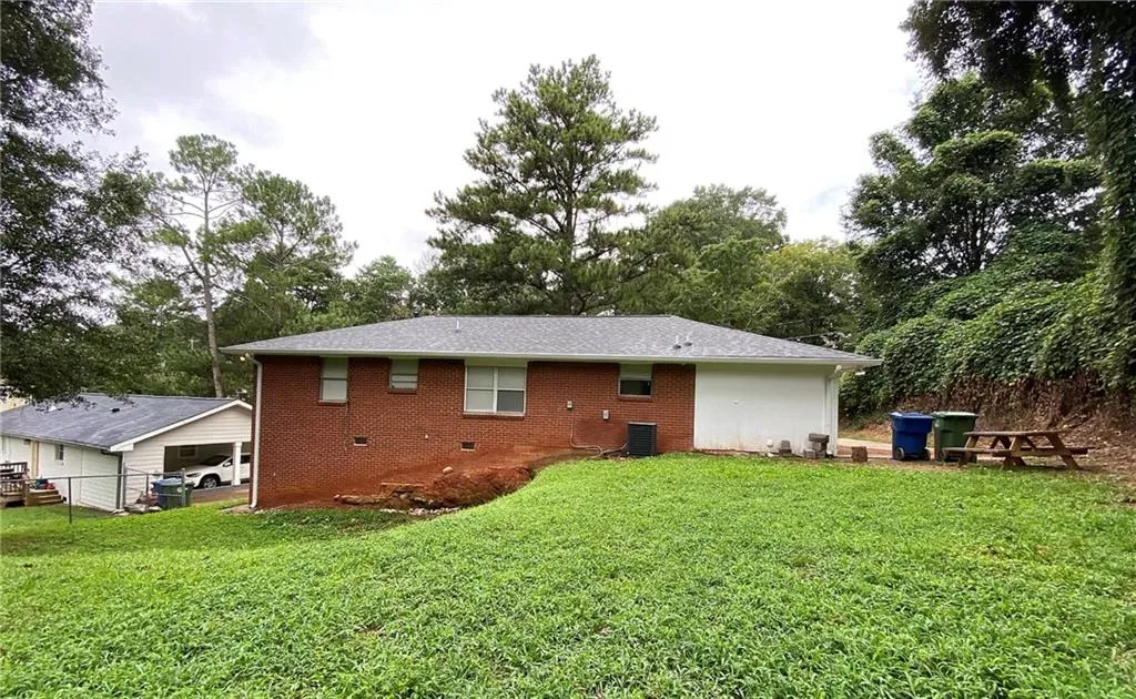 Rear view of house featuring crawl space, brick siding, and view of scattered trees