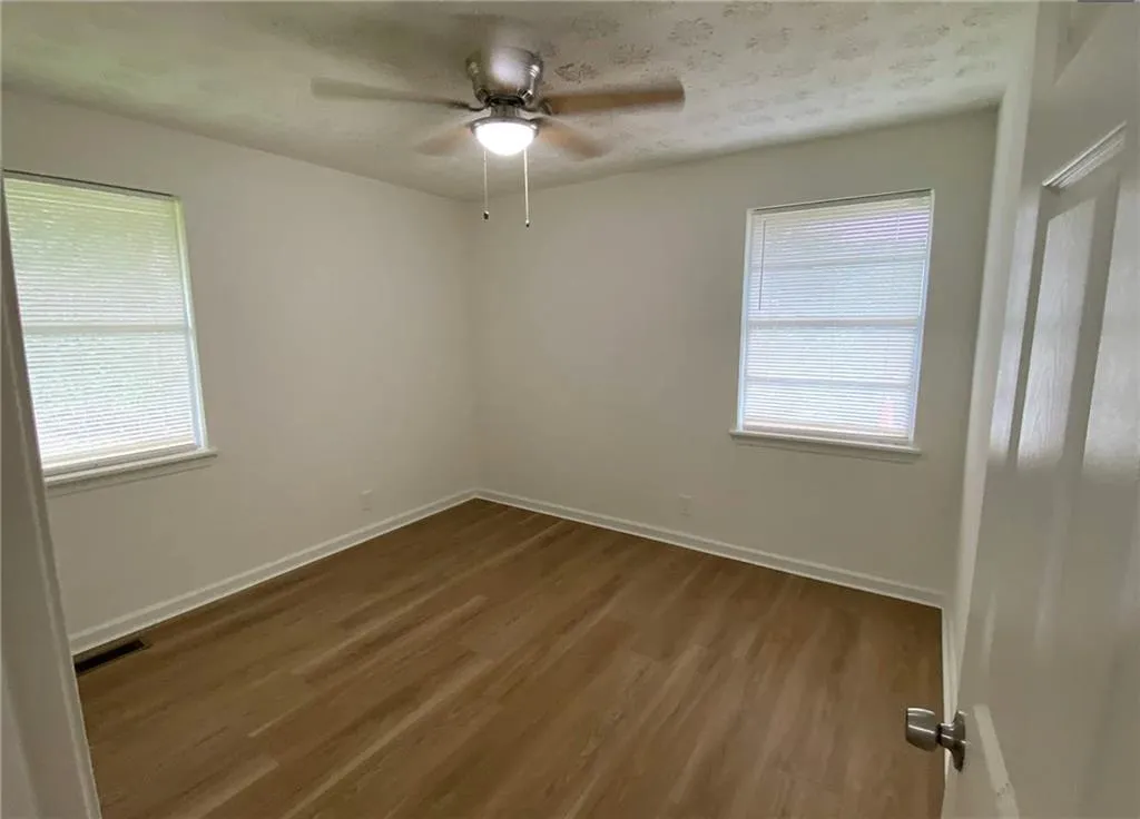 Empty room featuring dark wood-style floors and a ceiling fan