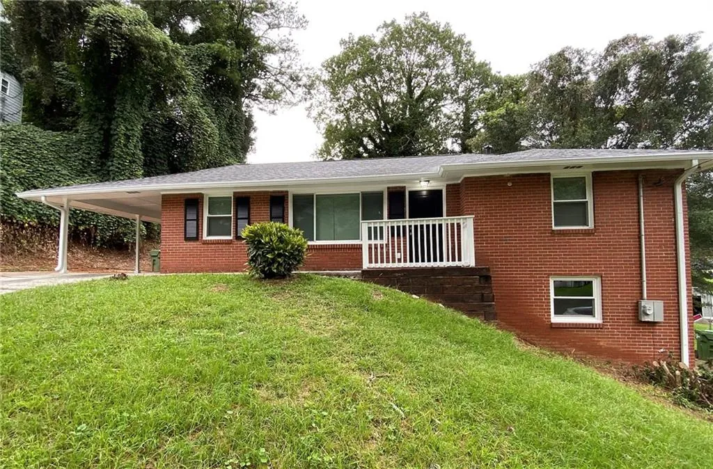 Single story home featuring covered porch, a front yard, brick siding, a carport, and concrete driveway