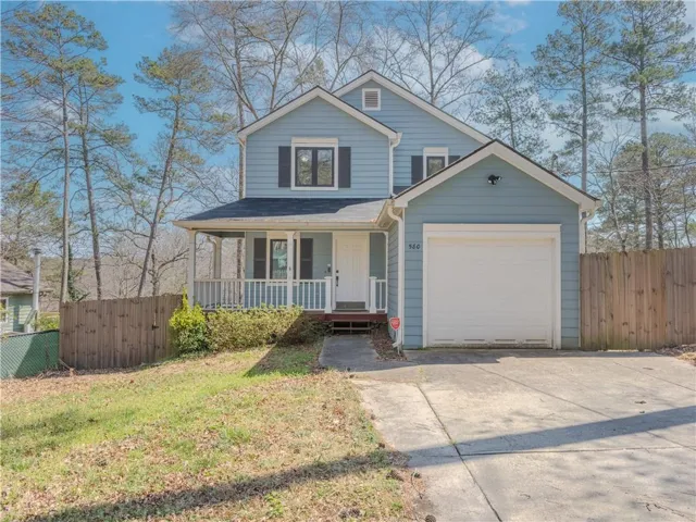 Traditional-style house with a porch, an attached garage, and driveway