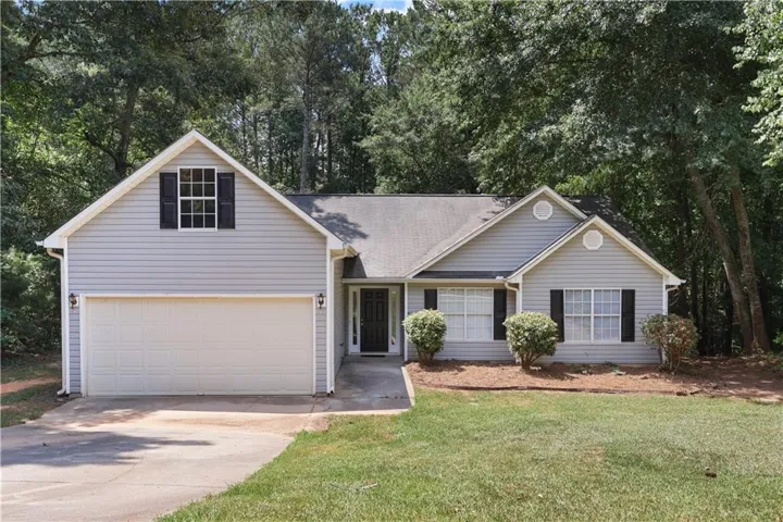 Single-story residence featuring light gray siding, a two-car garage, and dark window shutters