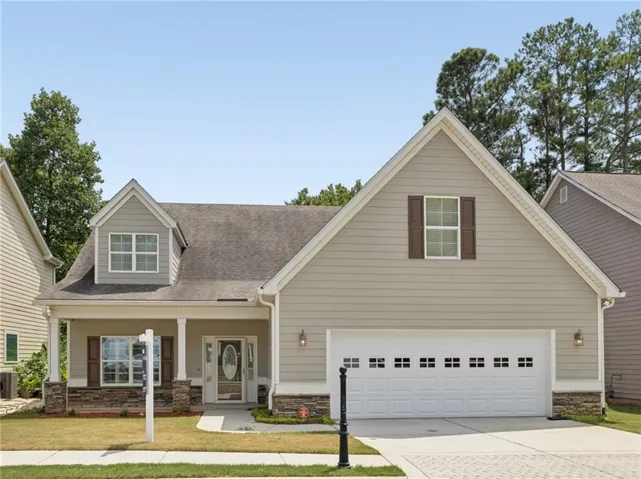 Gable roofline, horizontal siding exterior, stone facade accents, covered porch entrance, and an attached two-car garage