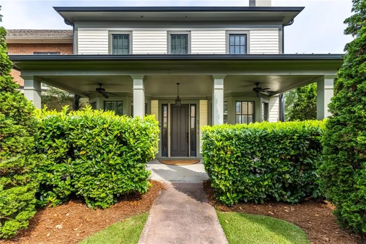Covered porch featuring ceiling fans, a dark-paneled entry door, and vertical siding