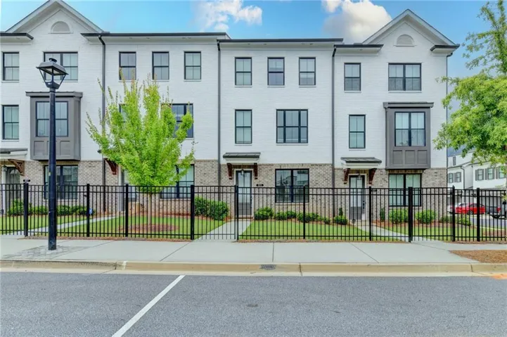 Contemporary townhome facade featuring white painted brick and dark trim windows