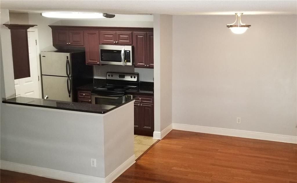 Kitchen with kitchen peninsula, light wood-type flooring, appliances with stainless steel finishes, and decorative light fixtures