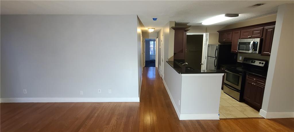 Kitchen featuring light wood-type flooring, appliances with stainless steel finishes, and dark brown cabinetry