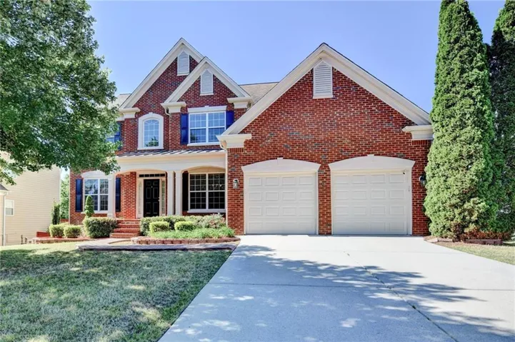 Brick exterior with white trim, a covered entry porch, a two-car garage, and a concrete driveway