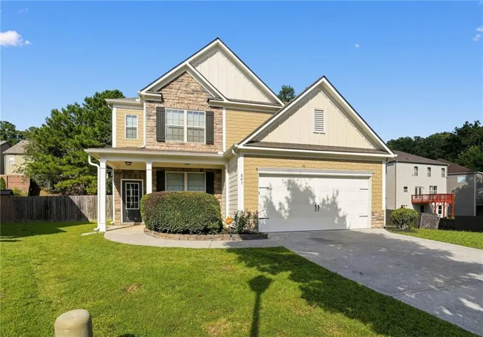 Two-story exterior with stone and siding accents, covered front entry, attached garage, and paved driveway