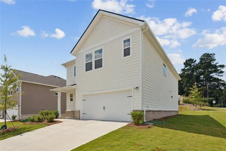 View of front of property featuring an attached garage, a front yard, and concrete driveway