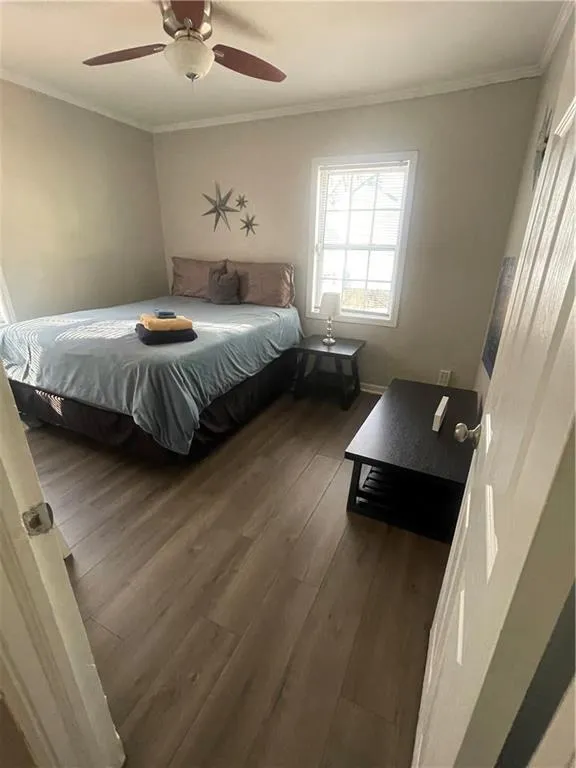 Bedroom featuring dark hardwood / wood-style flooring, ceiling fan, and crown molding