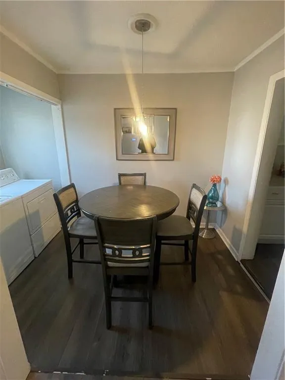 Dining room featuring independent washer and dryer, dark wood-type flooring, and ornamental molding