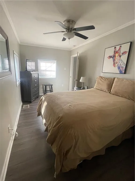 Bedroom featuring ceiling fan, dark hardwood / wood-style floors, and crown molding