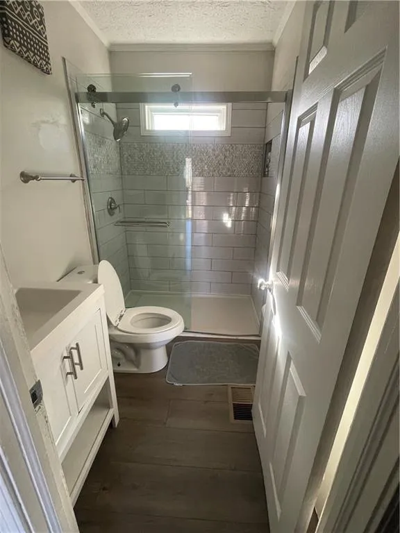 Bathroom with walk in shower, ornamental molding, vanity, hardwood / wood-style flooring, and toilet