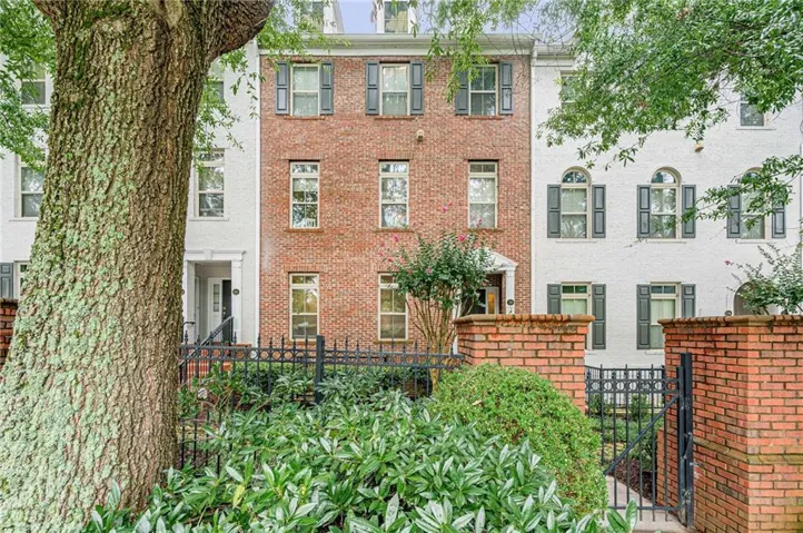 Three-story townhome featuring a brick facade with shuttered windows