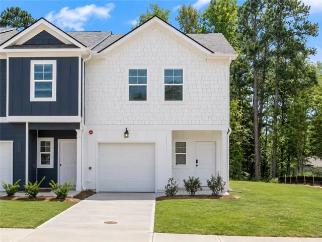 Contemporary exterior with white shake siding, two-car garage, concrete driveway, and established greenery