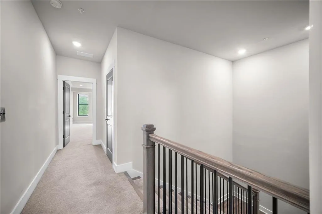 Carpeted hallway with recessed lighting, white trim, and dark interior doors