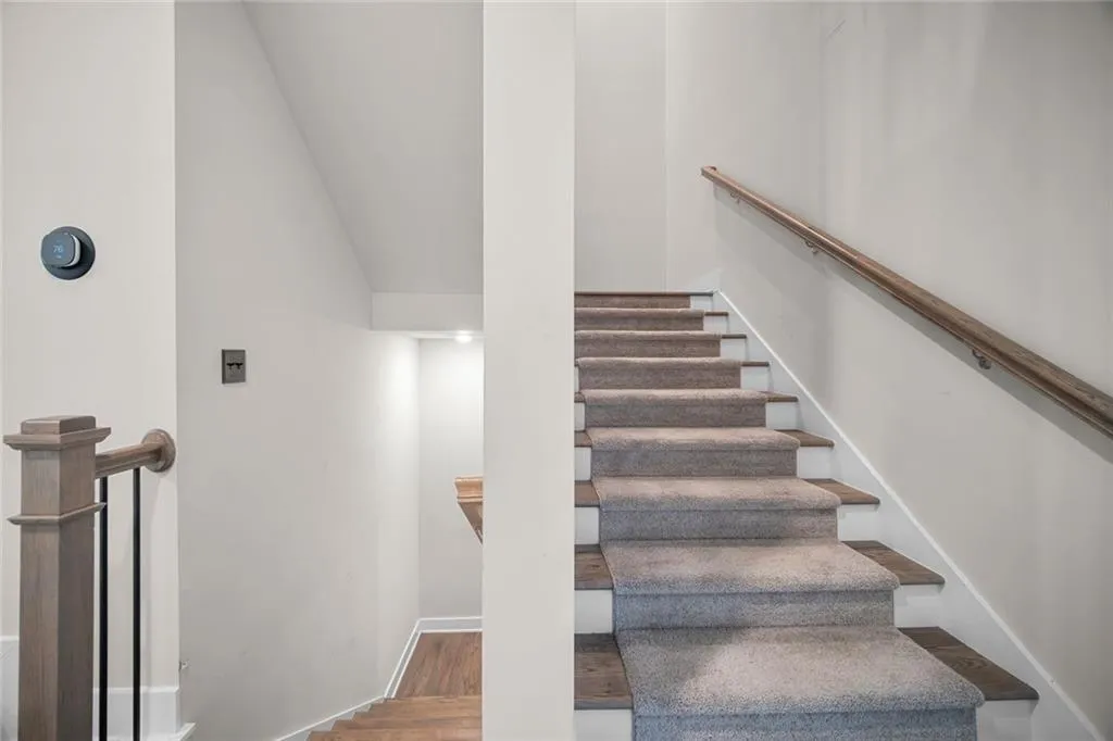 Carpeted staircase with wood finish treads and a wood handrail