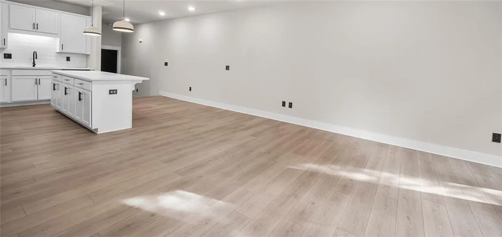 Open-concept room featuring wood-finish flooring, recessed lighting, and a kitchen island with a quartz countertop