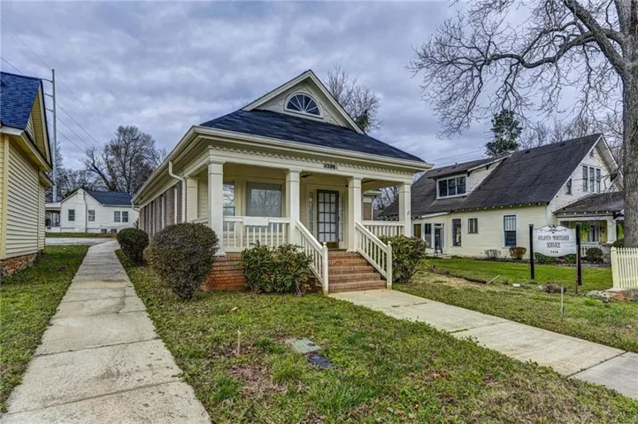 Exterior featuring a prominent front porch with white columns, brick foundation, and a dark shingle roof