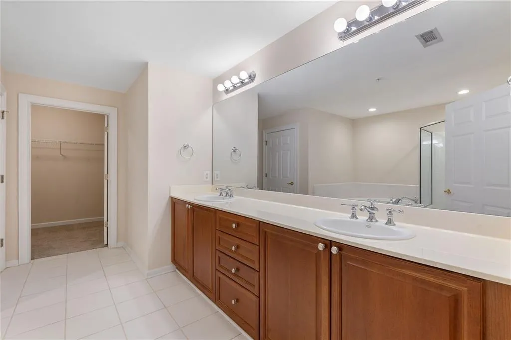 Bathroom with a spacious closet, double vanity, and light tile patterned floors