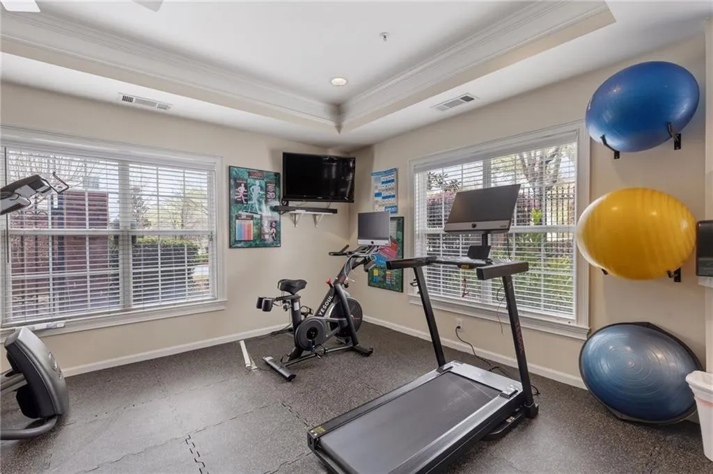 Workout area featuring crown molding, dark flooring, healthy amount of natural light, and a tray ceiling