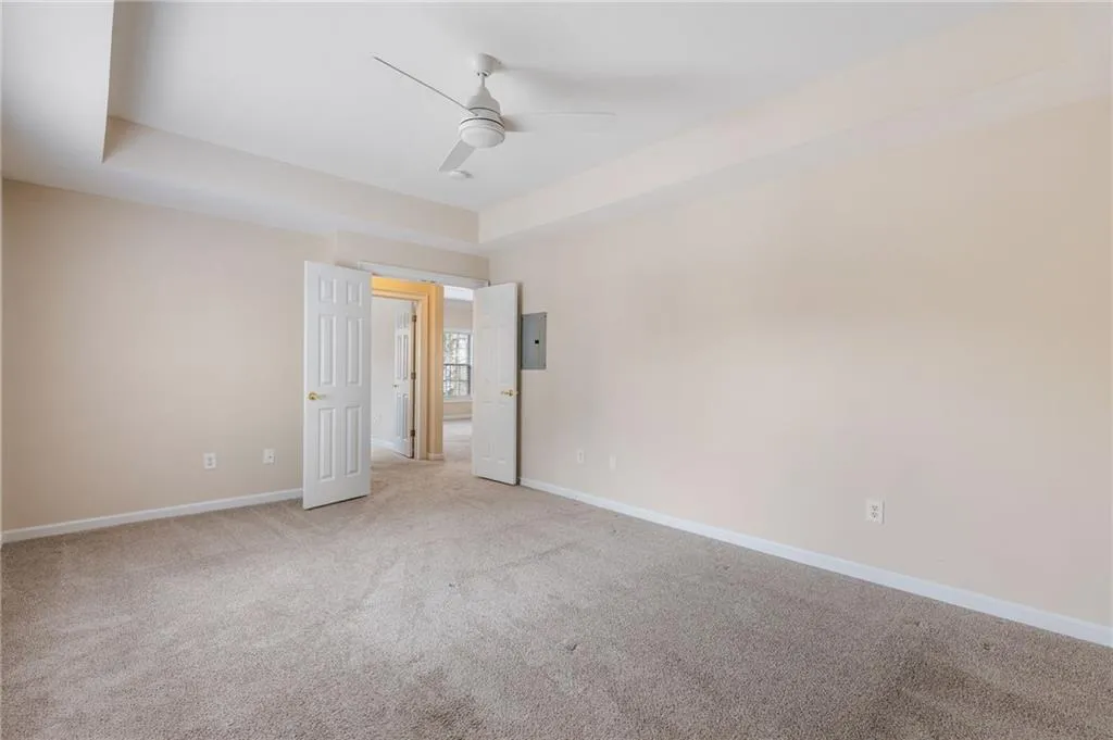 Spare room with a tray ceiling, light colored carpet, and a ceiling fan