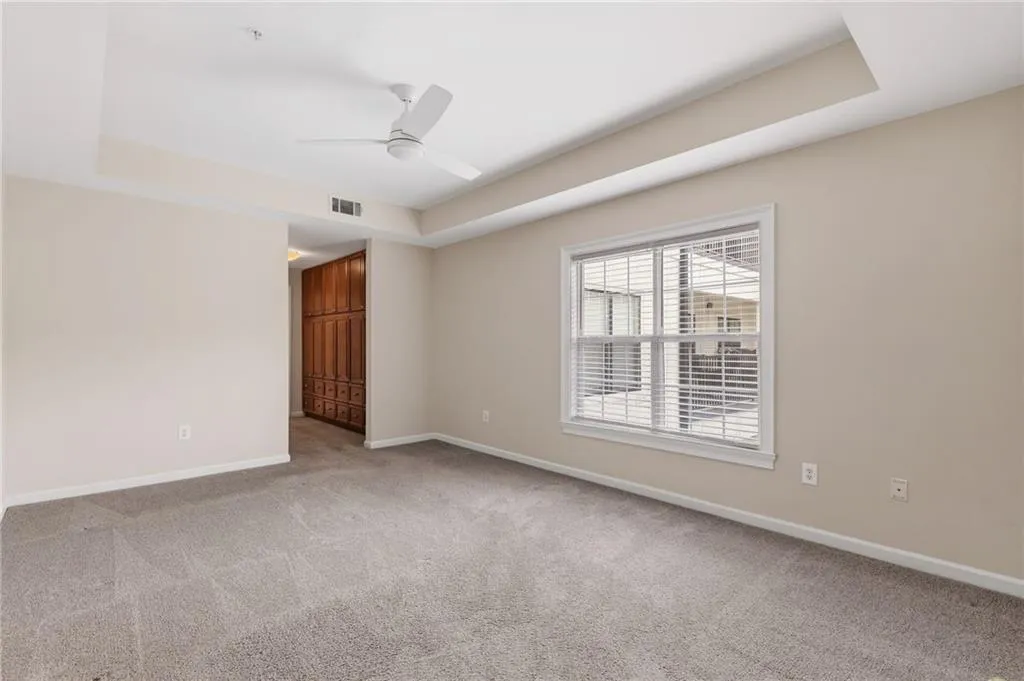 Spare room with a tray ceiling, a ceiling fan, and light colored carpet