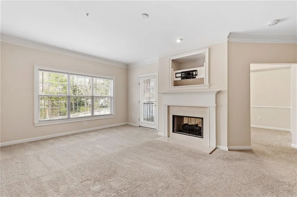 Unfurnished living room featuring light carpet, ornamental molding, and a tile fireplace