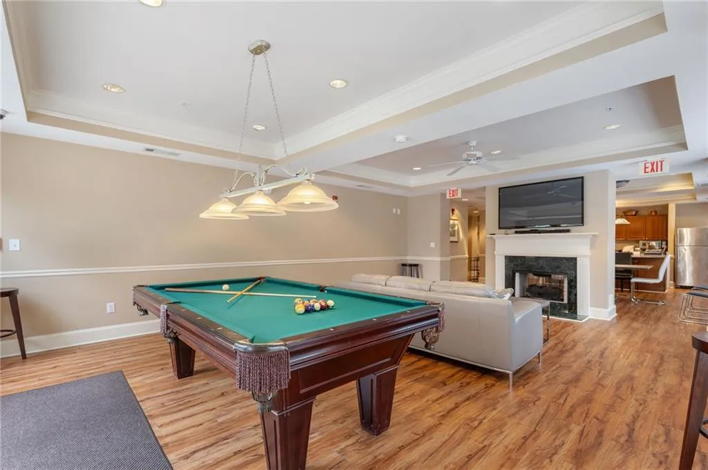 Game room featuring a raised ceiling, billiards, ornamental molding, a premium fireplace, and a ceiling fan