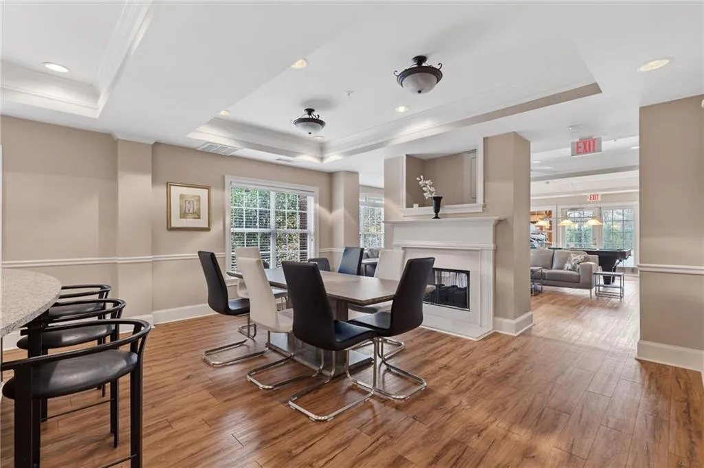 Dining space featuring light wood-type flooring, a tray ceiling, a multi sided fireplace, crown molding, and recessed lighting