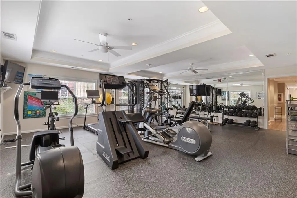 Exercise room featuring ceiling fan, ornamental molding, a tray ceiling, and recessed lighting