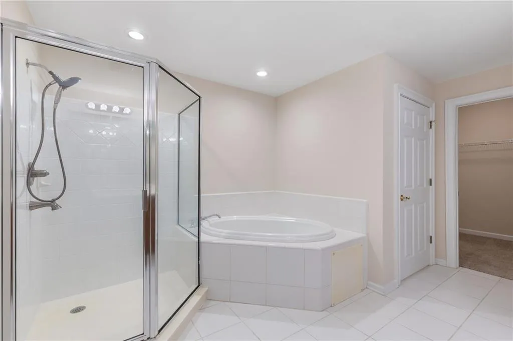 Bathroom featuring a stall shower, a garden tub, light tile patterned floors, a spacious closet, and recessed lighting