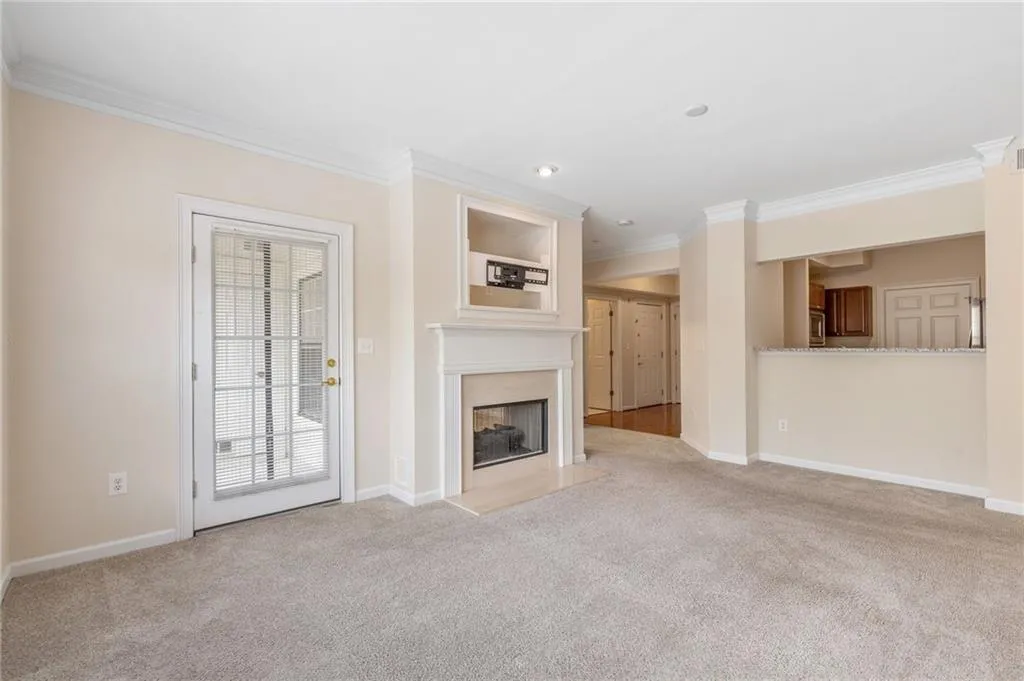 Unfurnished living room featuring ornamental molding, light colored carpet, and a premium fireplace