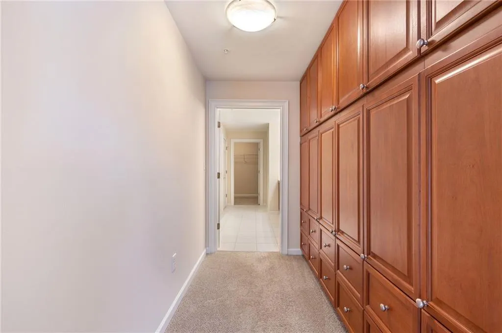 Hall featuring light colored carpet and baseboards