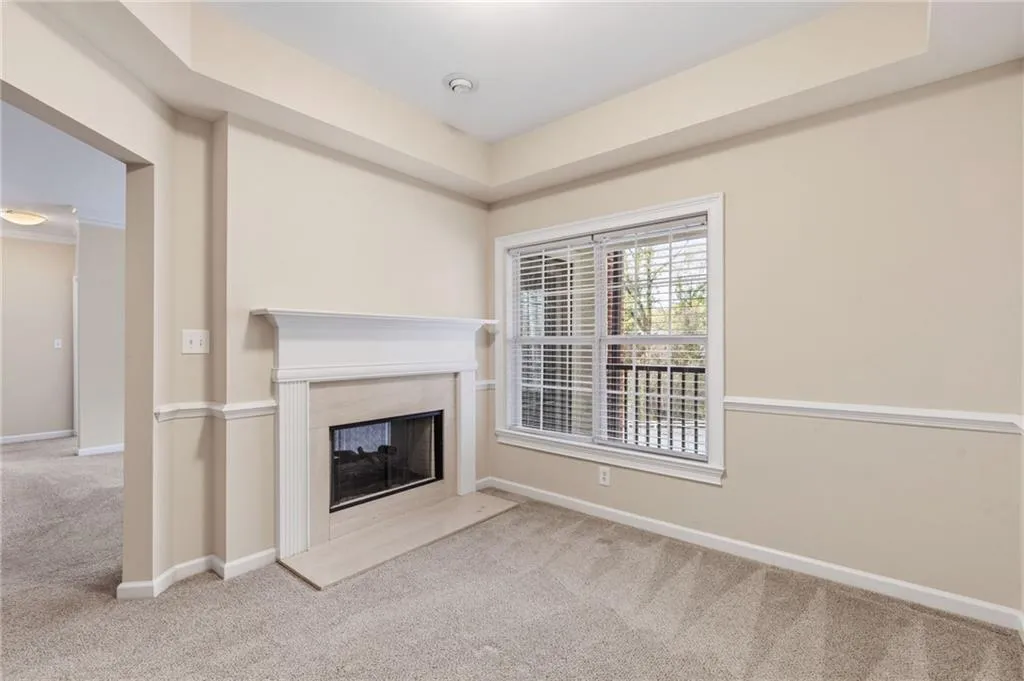 Unfurnished living room featuring light carpet, a high end fireplace, and a raised ceiling