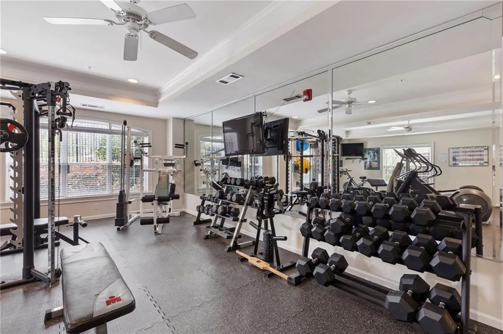 Exercise room featuring a ceiling fan, ornamental molding, a tray ceiling, and recessed lighting