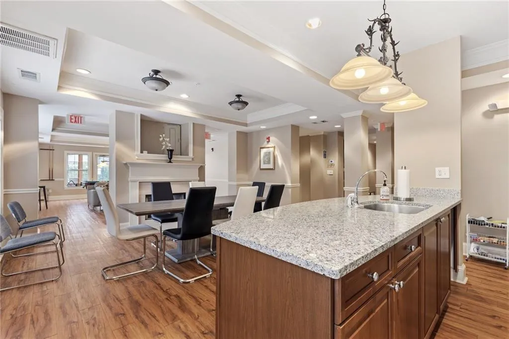 Kitchen featuring ornamental molding, light stone counters, hanging light fixtures, a peninsula, and wood finish cabinetry