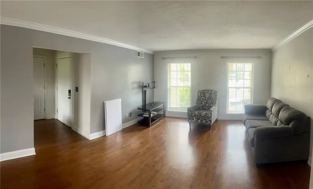 Living room with ornamental molding, wood finished floors, and baseboards