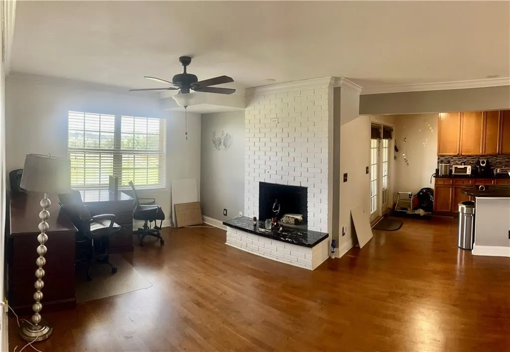 Living area featuring crown molding, a fireplace, dark wood-style flooring, a ceiling fan, and baseboards