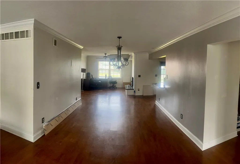 Dining area featuring wood finished floors, ornamental molding, baseboards, and a chandelier
