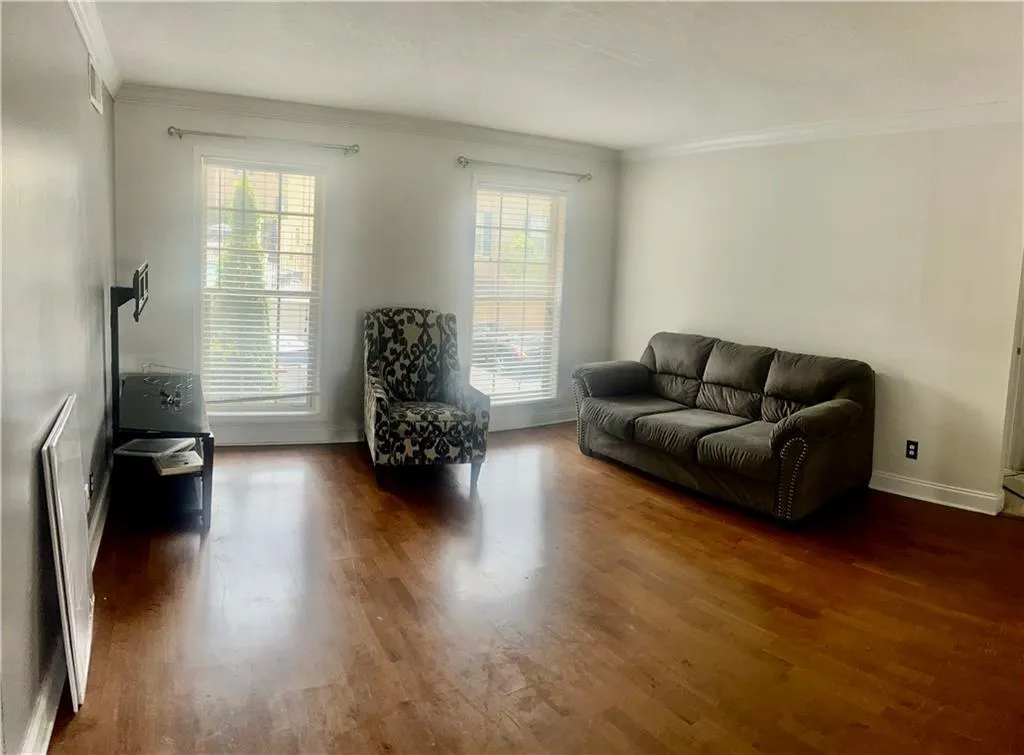Living area featuring crown molding, healthy amount of natural light, dark wood-style floors, and baseboards