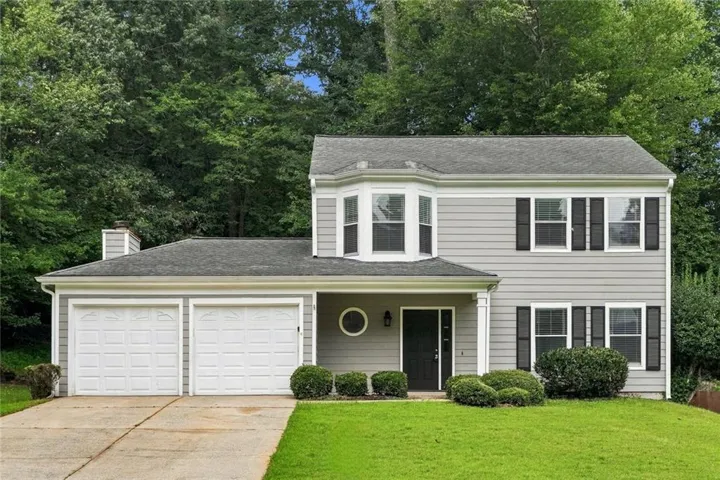 Gray siding exterior with a two-car garage, bay window, front entry with a portico, and contrasting black shutters