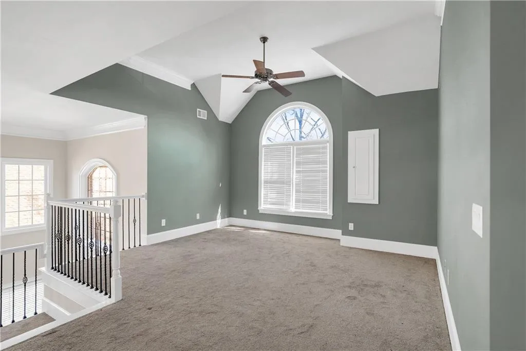 Empty room with carpet floors, visible vents, crown molding, and baseboards
