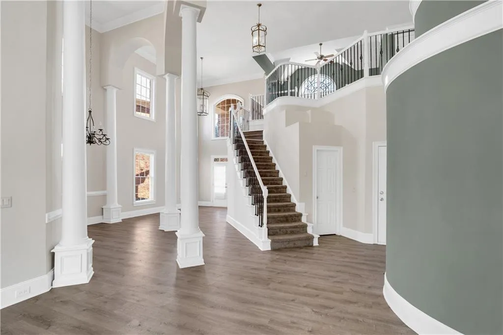 Foyer with ornate columns, ornamental molding, dark wood finished floors, and a ceiling fan